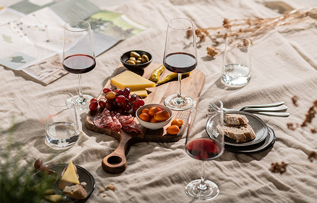 Weingläser und Essen ist auf einem Tuch platziert